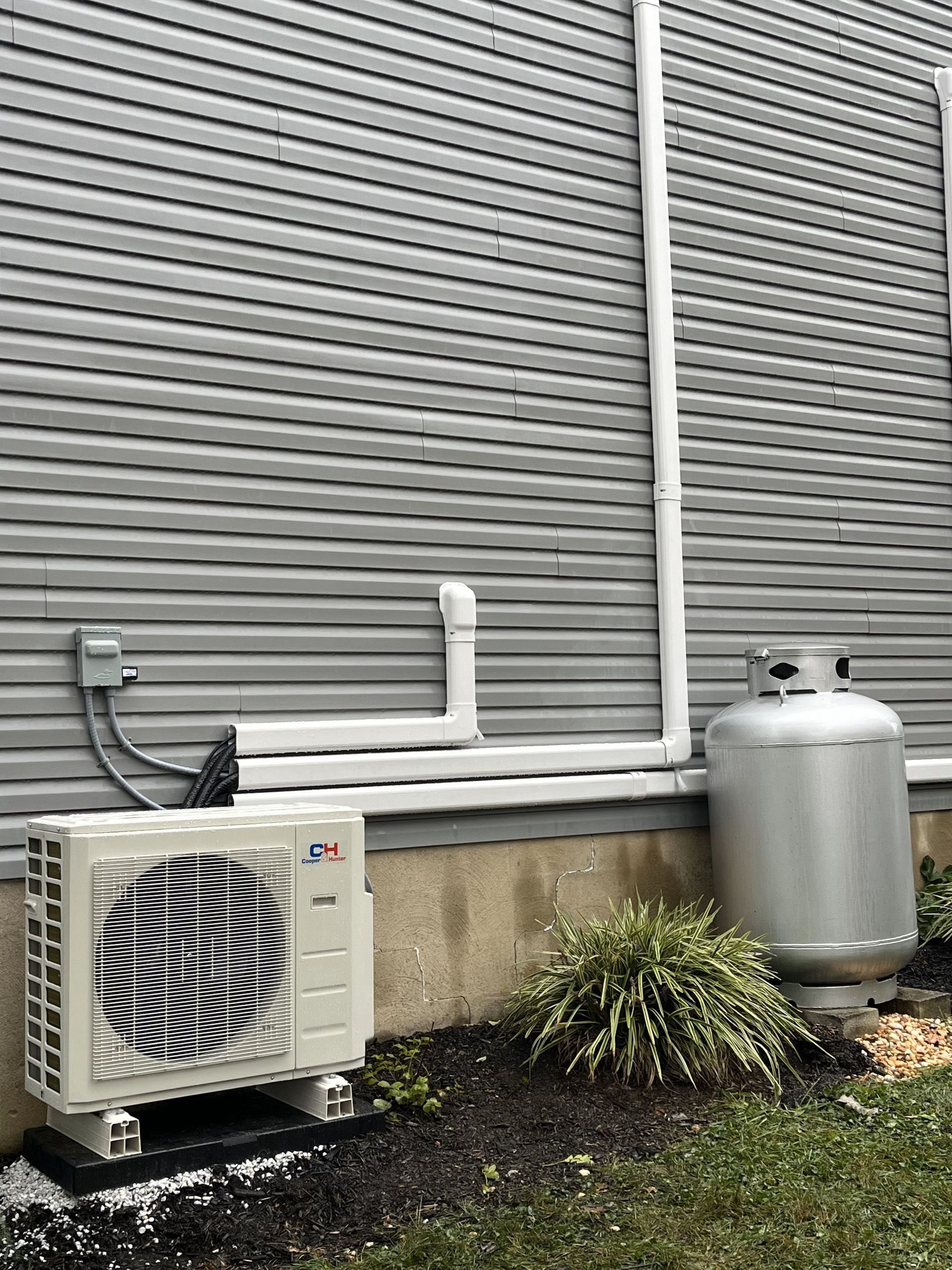 A propane tank is attached to the side of a house.