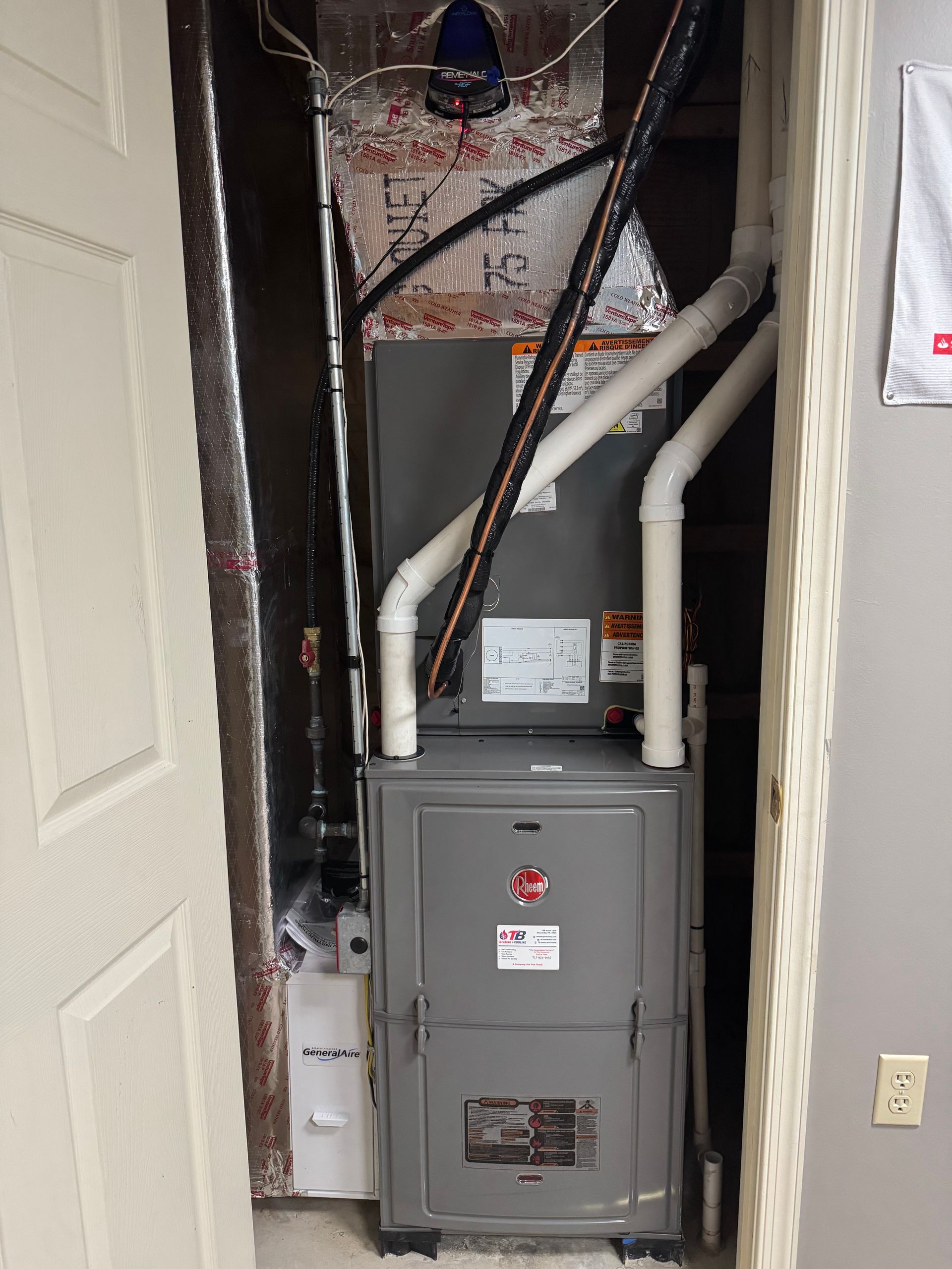 An air conditioner is sitting in a closet next to a door.