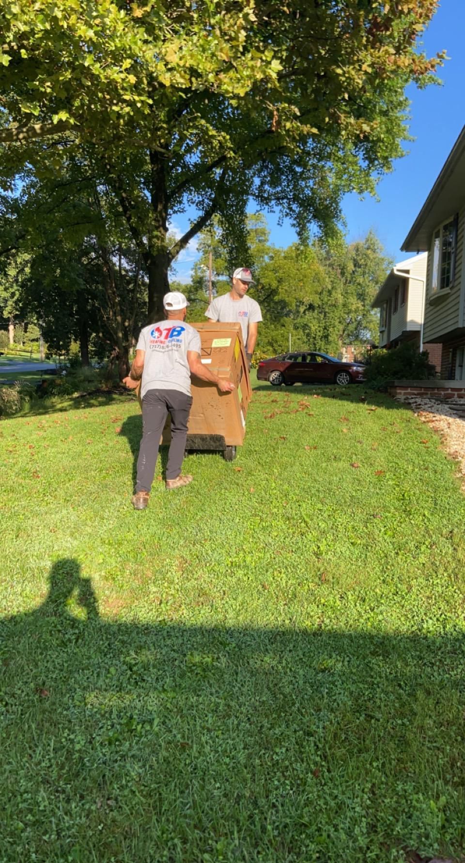 Two men are carrying a box up a grassy hill.