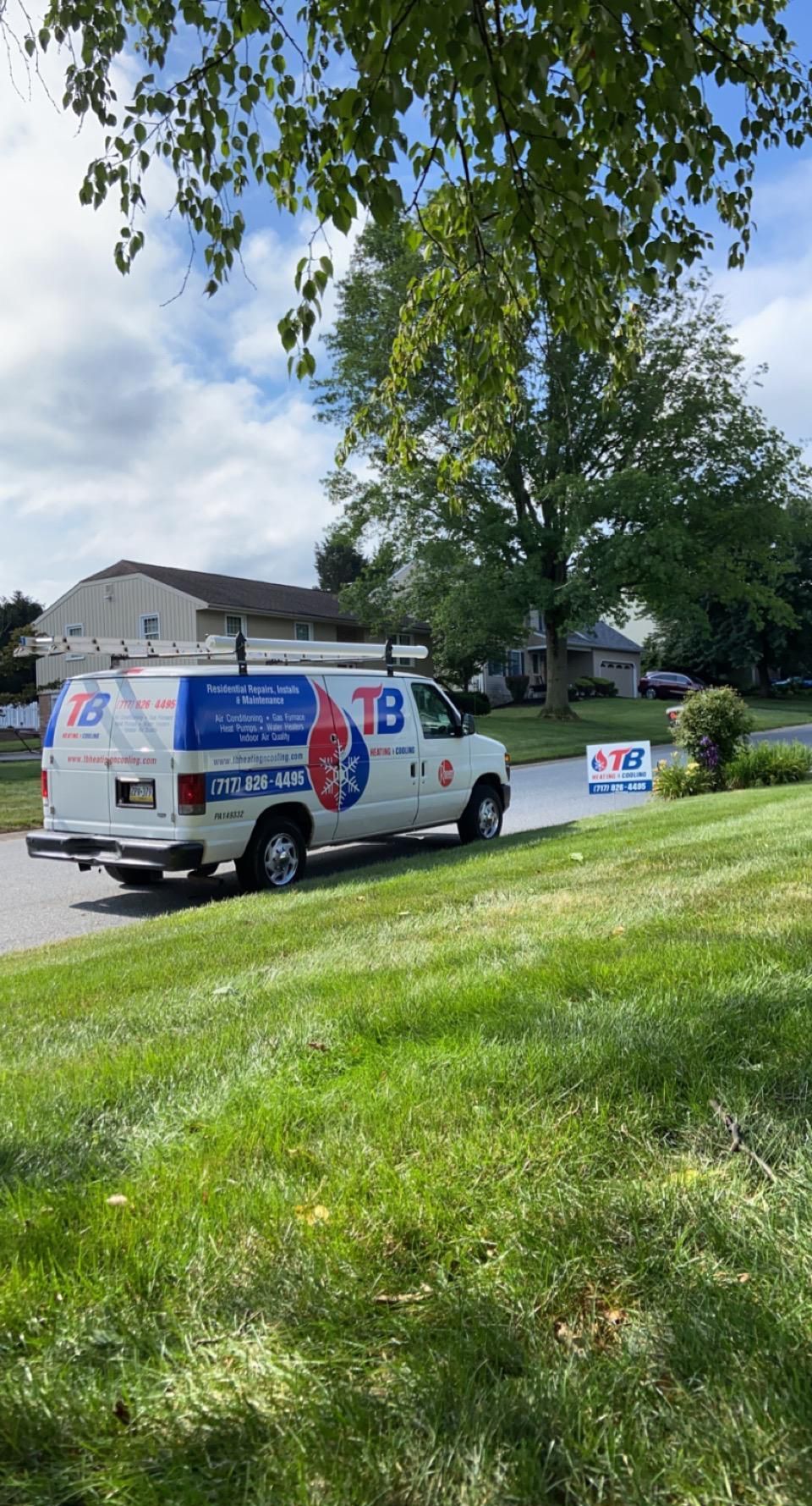 A white van is parked in the grass in front of a house.
