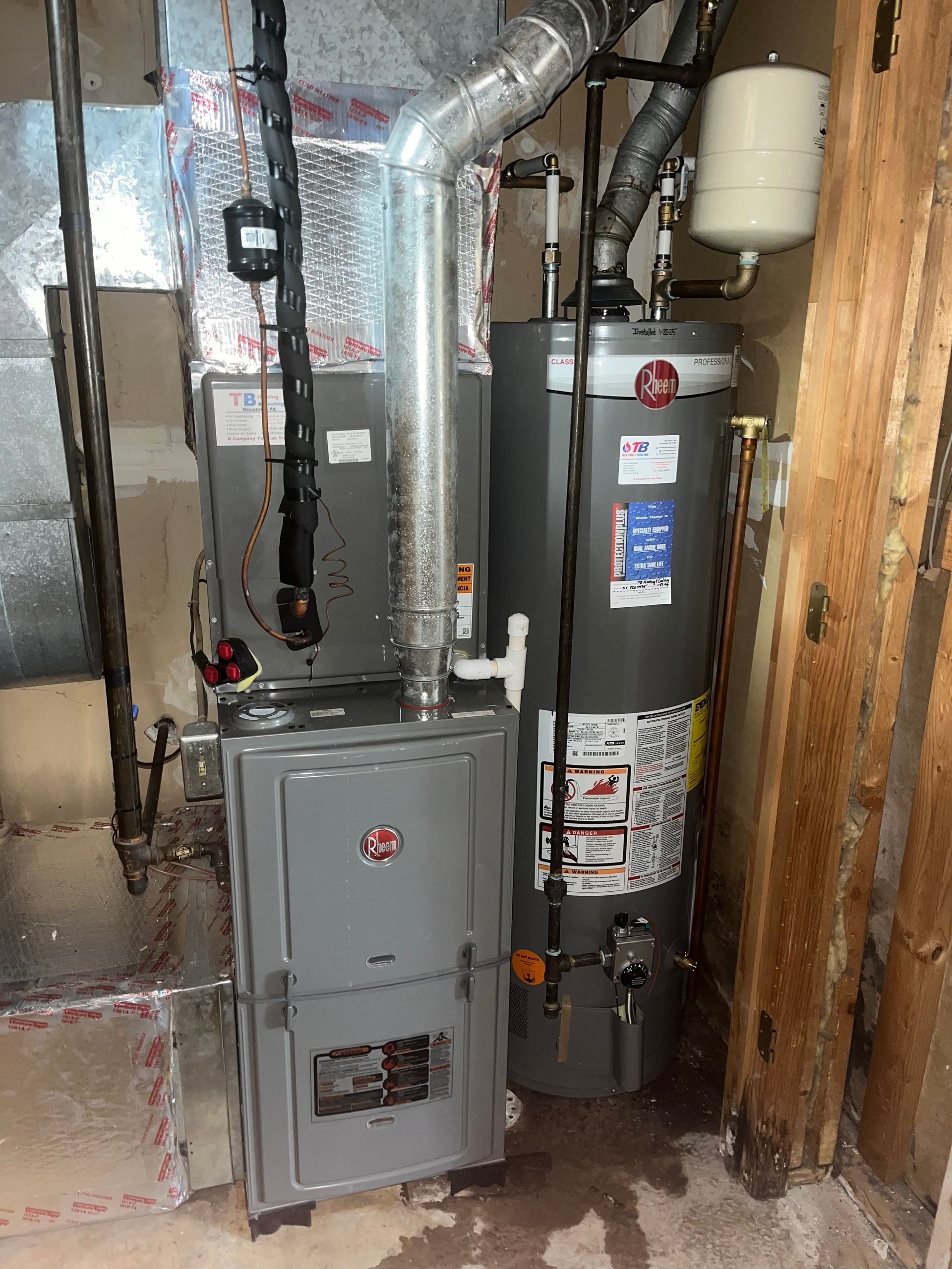 A water heater is sitting next to a furnace in a room.