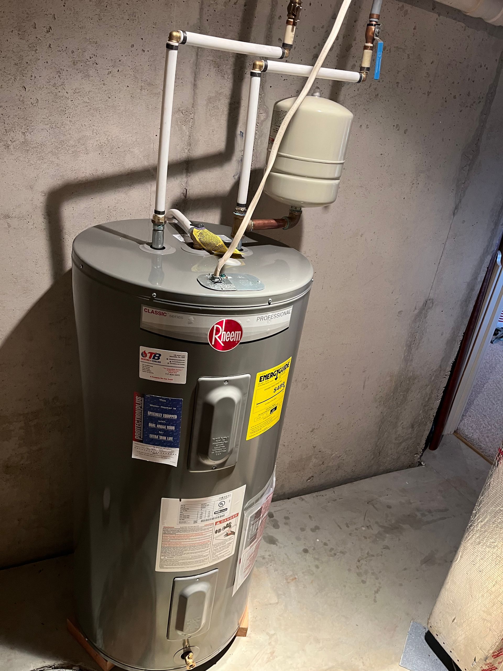 A water heater is sitting in a basement next to a wall.