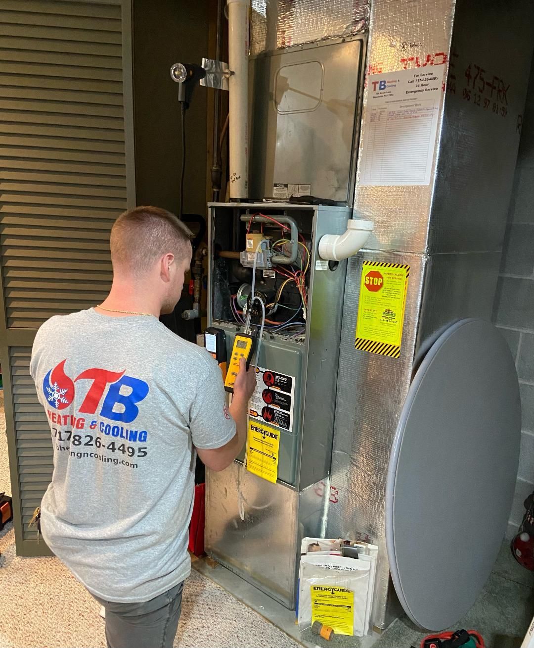 A man is working on an air conditioner in a basement.