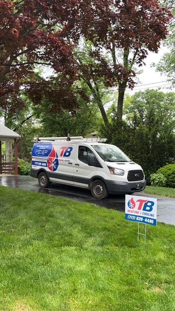 A white van is parked in the grass next to a sign.