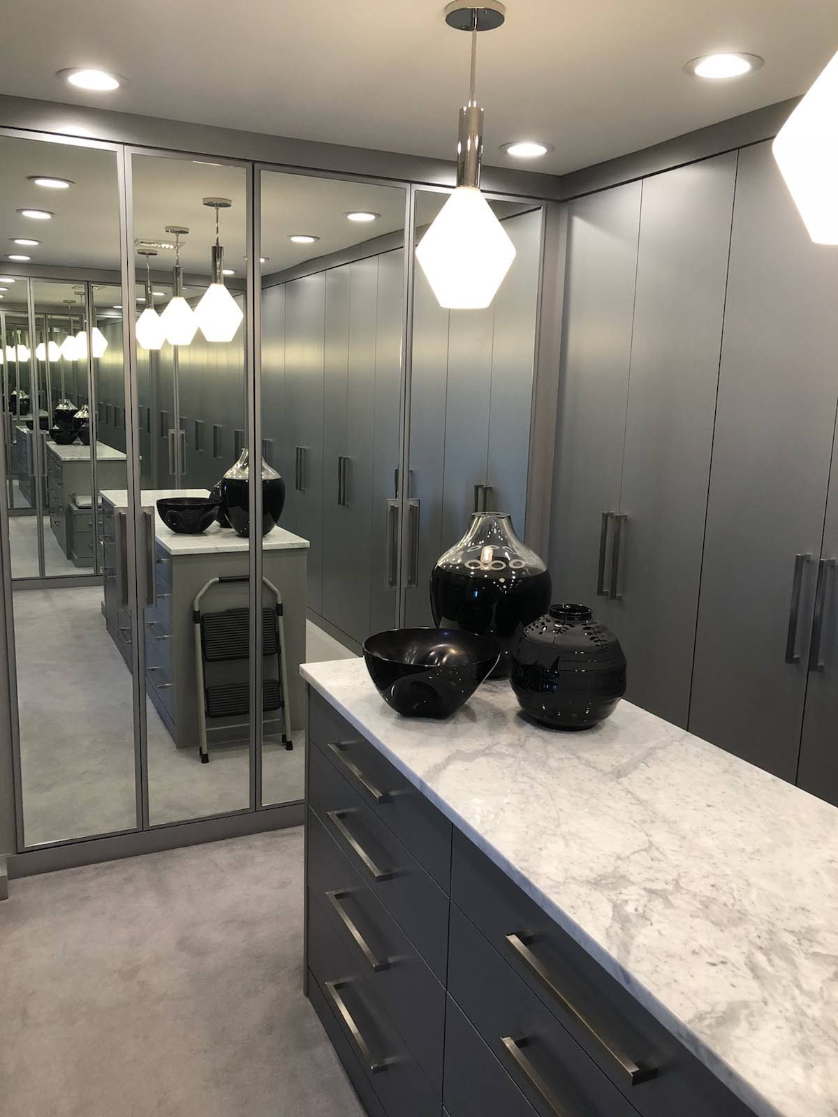 a walk in closet with a marble counter top and lots of mirrors.