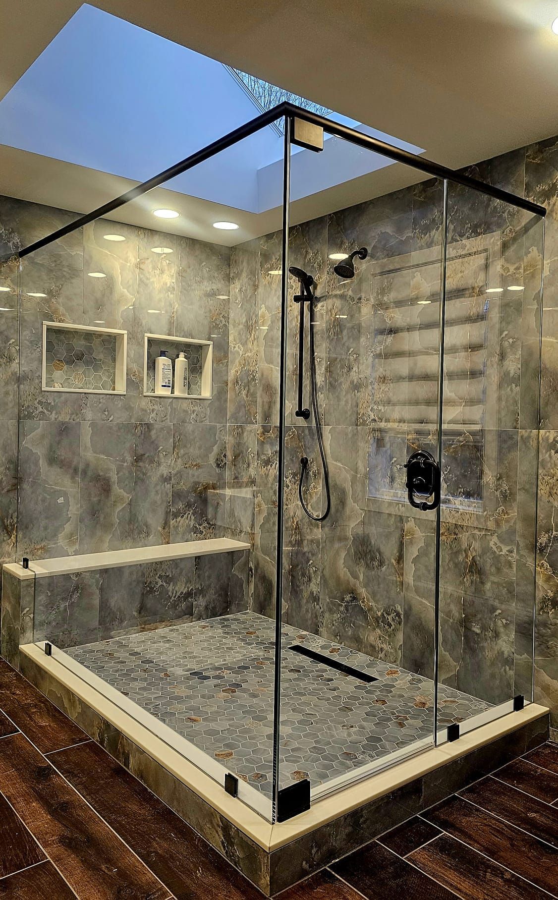 a bathroom with a walk in shower with a skylight above it.