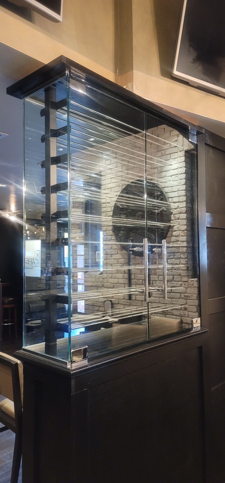 a glass wine cellar in a room with a brick wall.