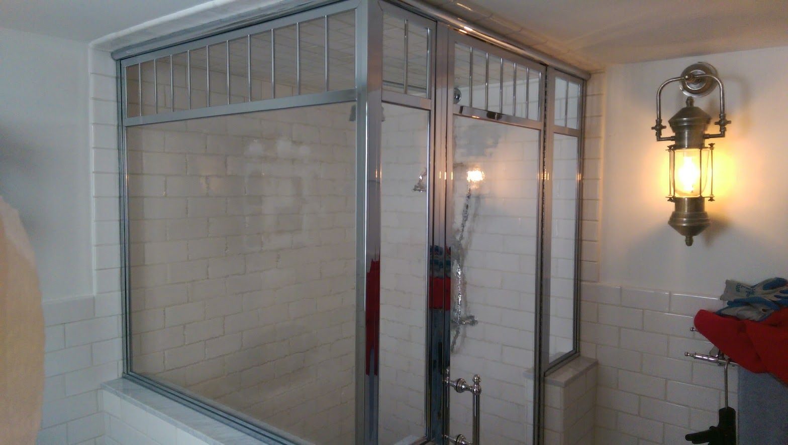 a bathroom with a shower stall and a lantern on the wall.