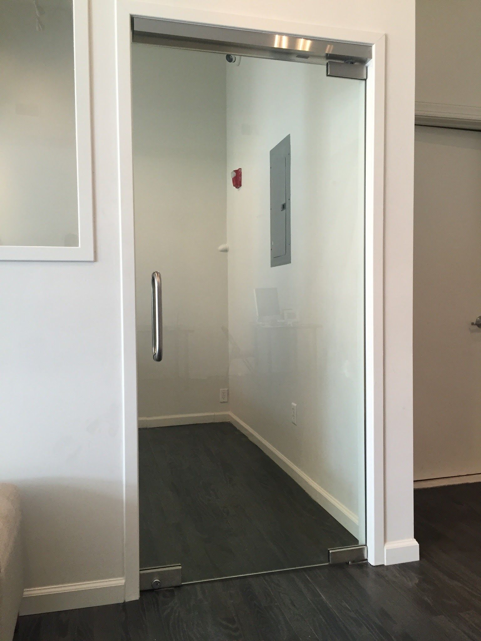 a glass door in a room with a fire extinguisher on the wall.
