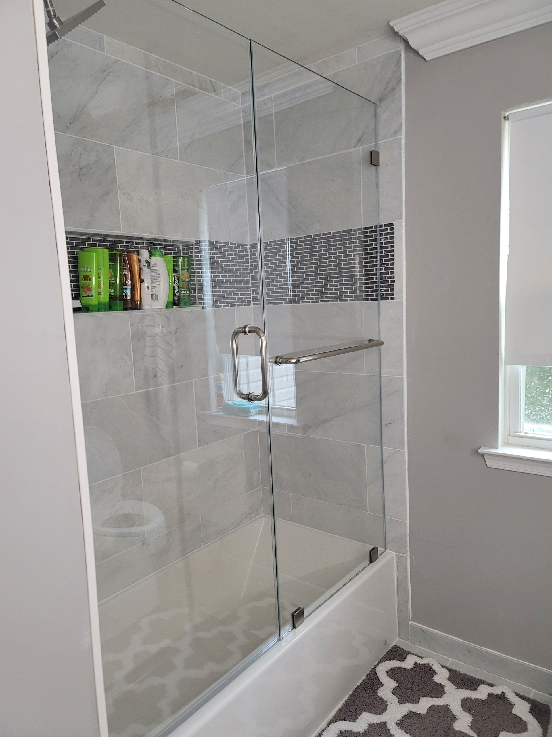 a bathroom with a bathtub and a glass shower door.