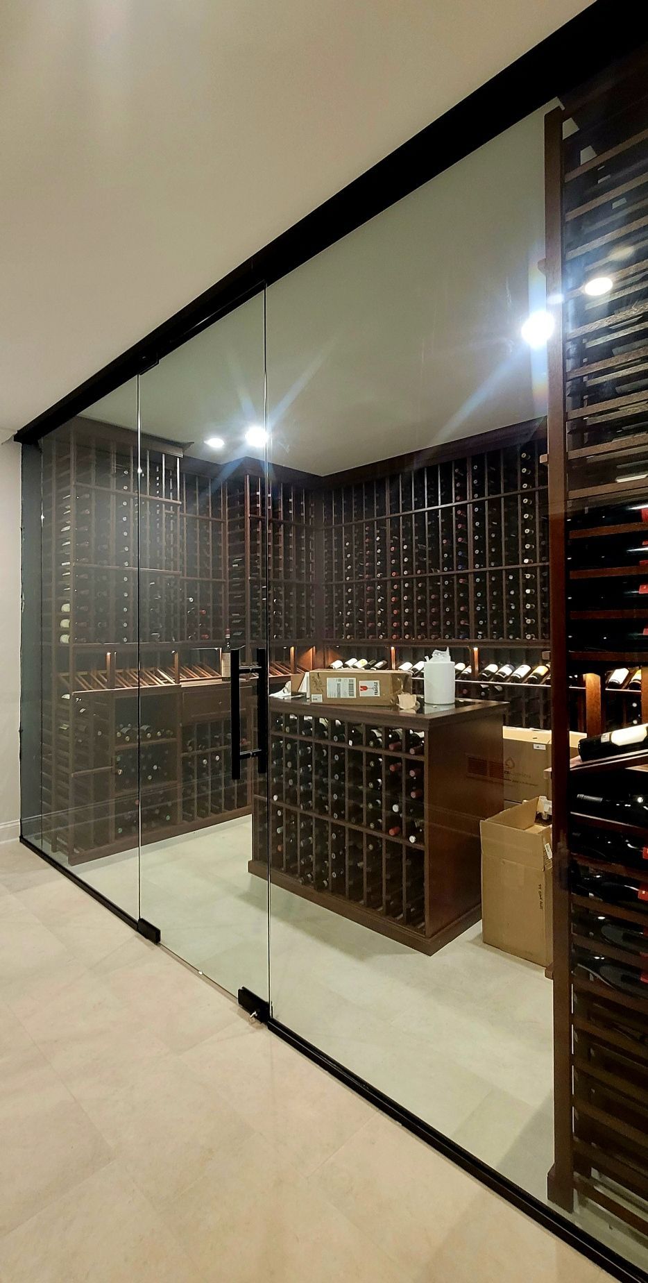 a wine cellar with a glass wall and lots of wine bottles.