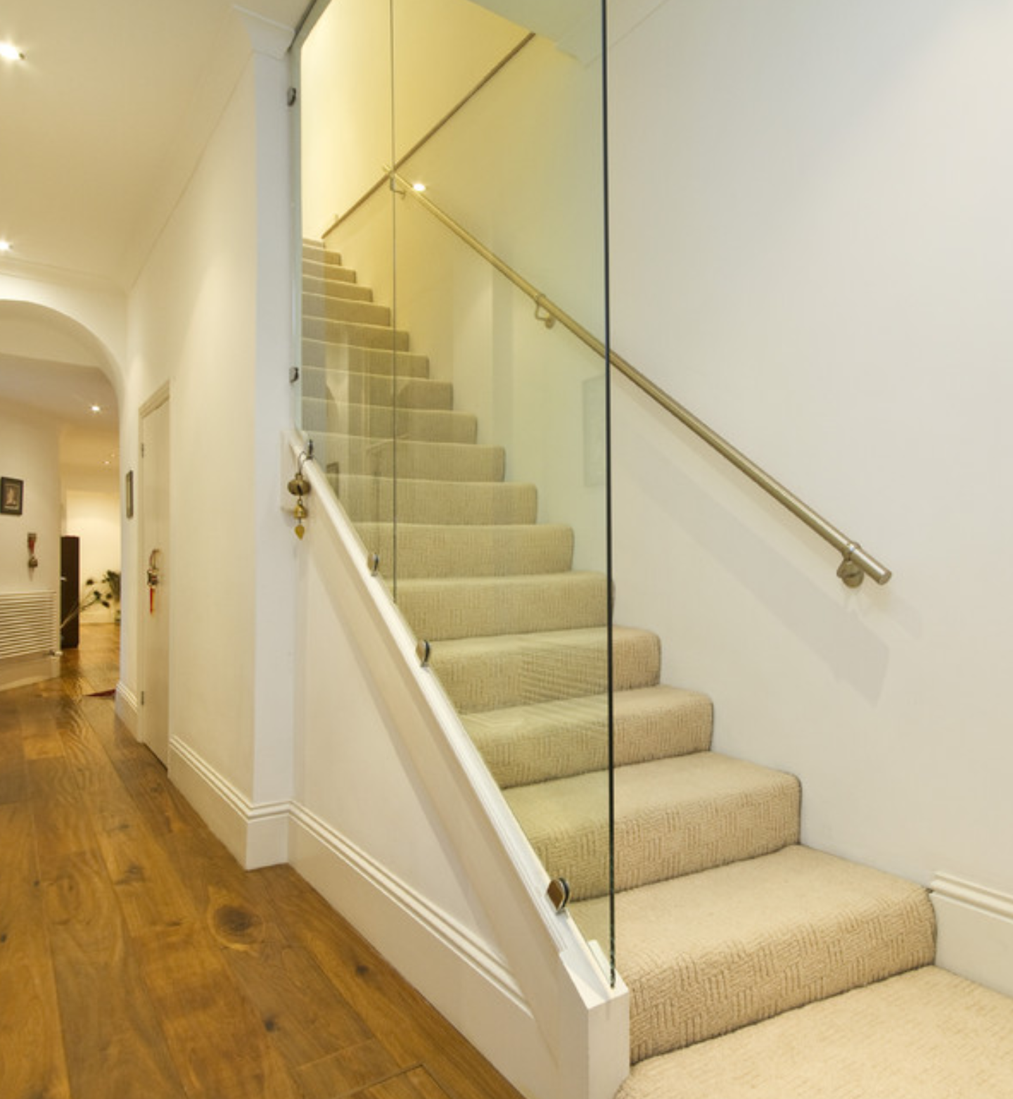 a staircase with a glass railing in a hallway.