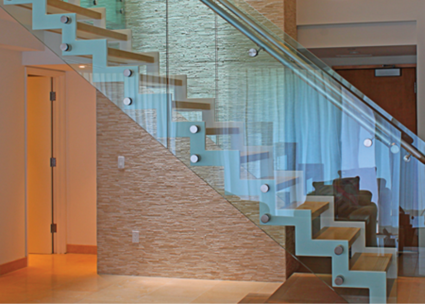 a modern staircase with a glass railing in a living room.