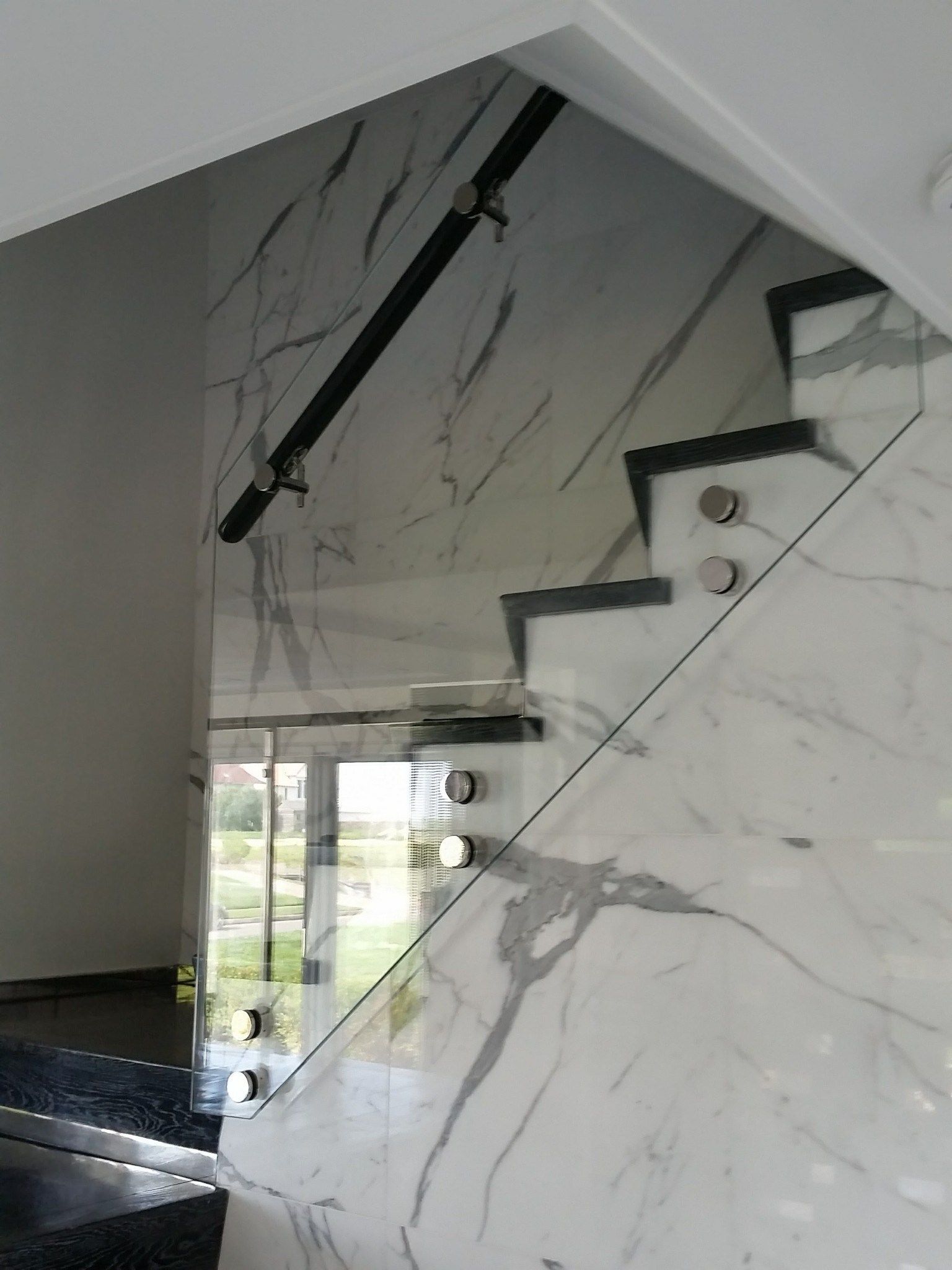 a staircase with marble steps and a glass railing.