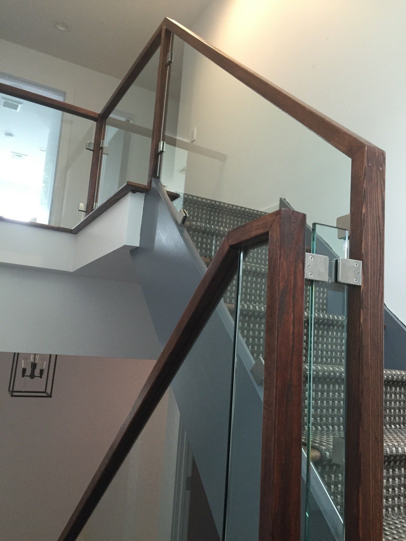 a staircase with a glass railing and a wooden handrail.