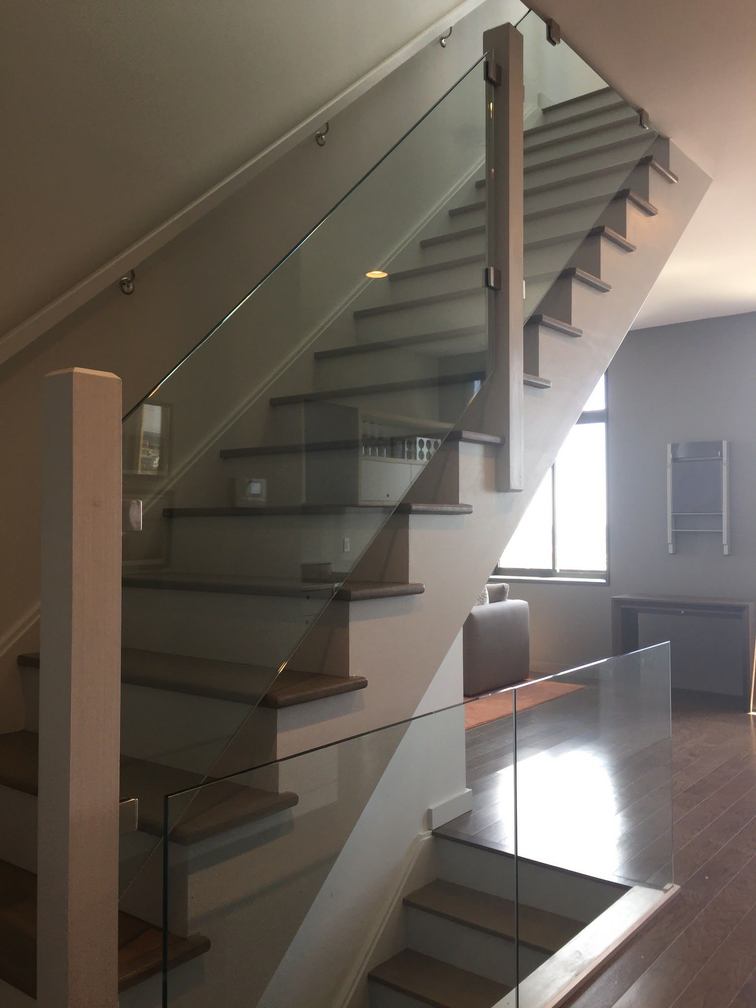 a staircase with a glass railing in a living room.