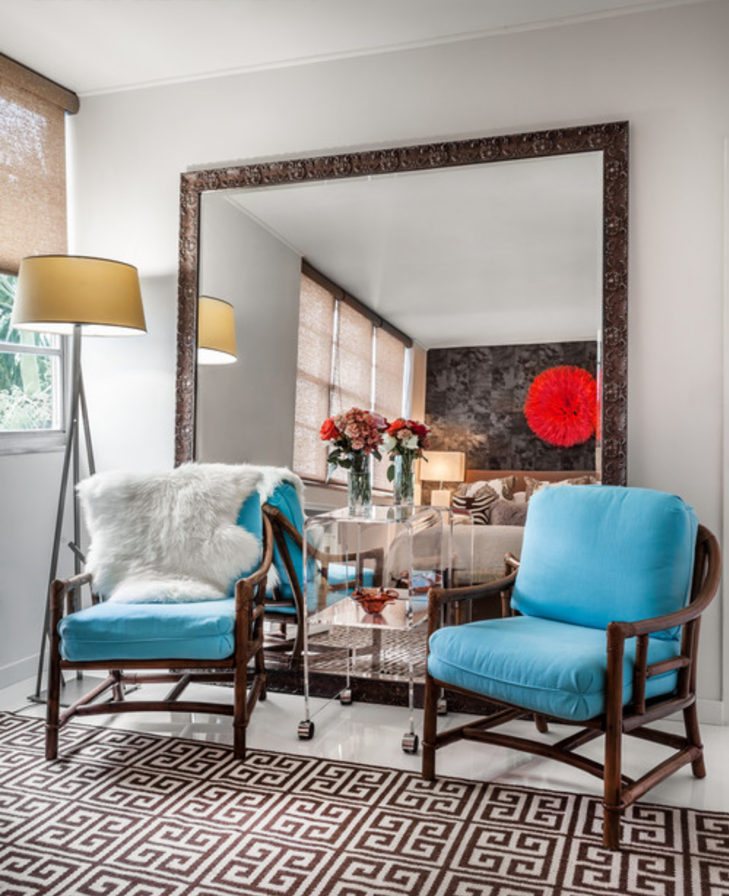a living room with two blue chairs and a large mirror.