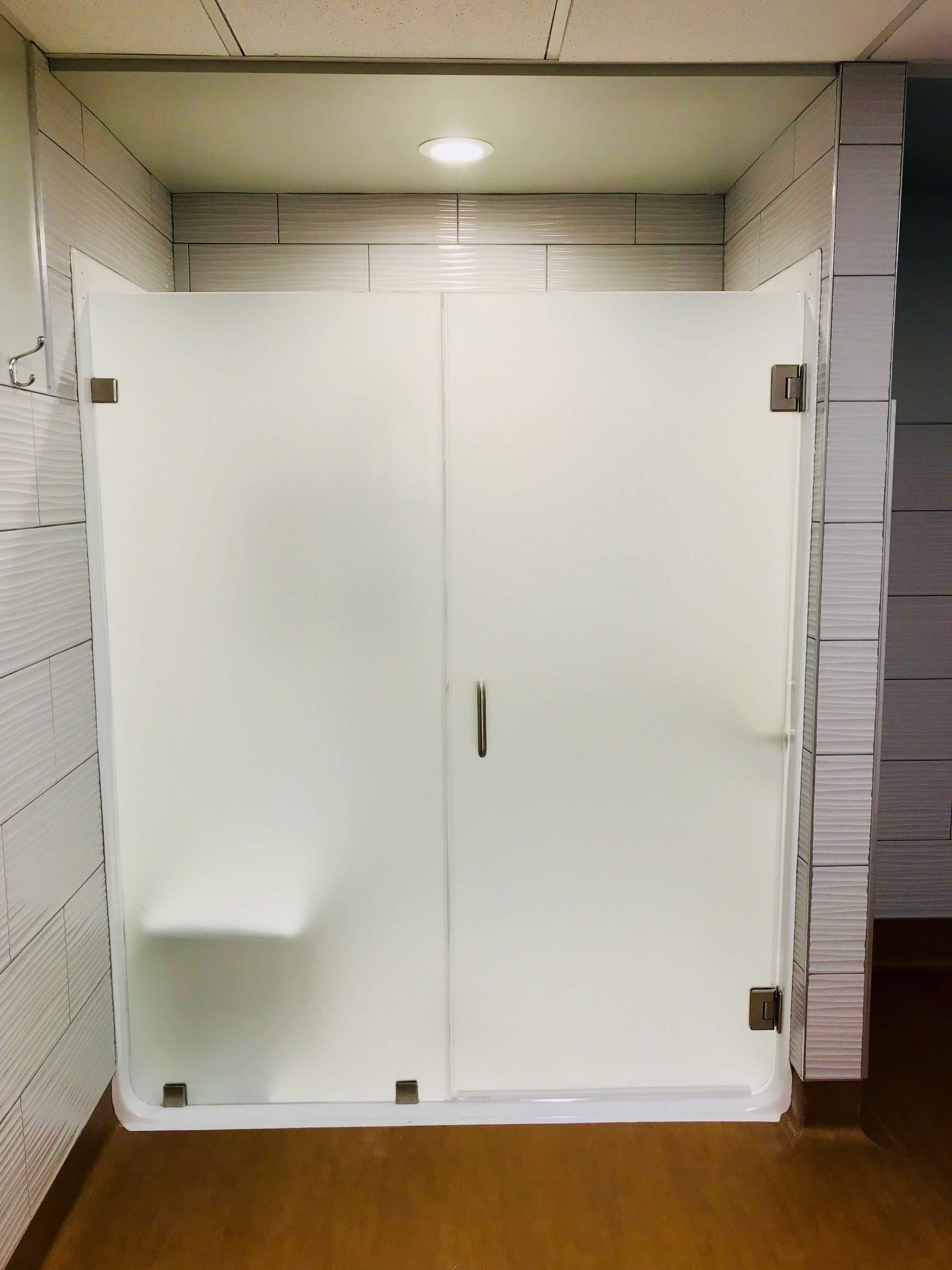 a bathroom with a glass shower door and a bench.