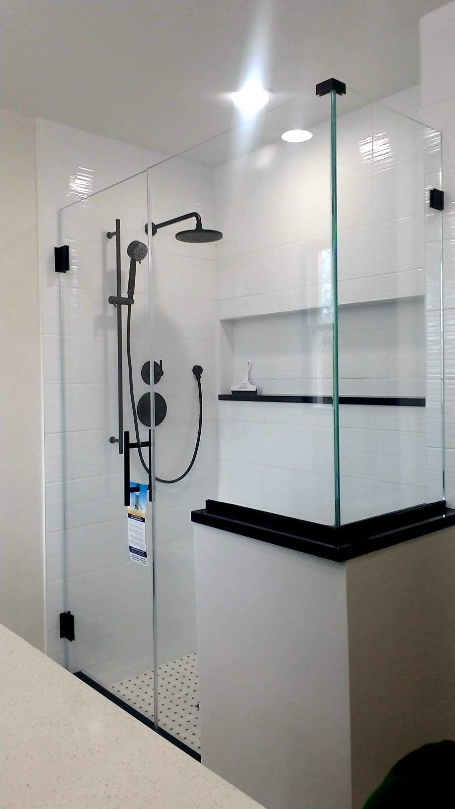 a shower stall with a glass door and a black shower head in a bathroom.