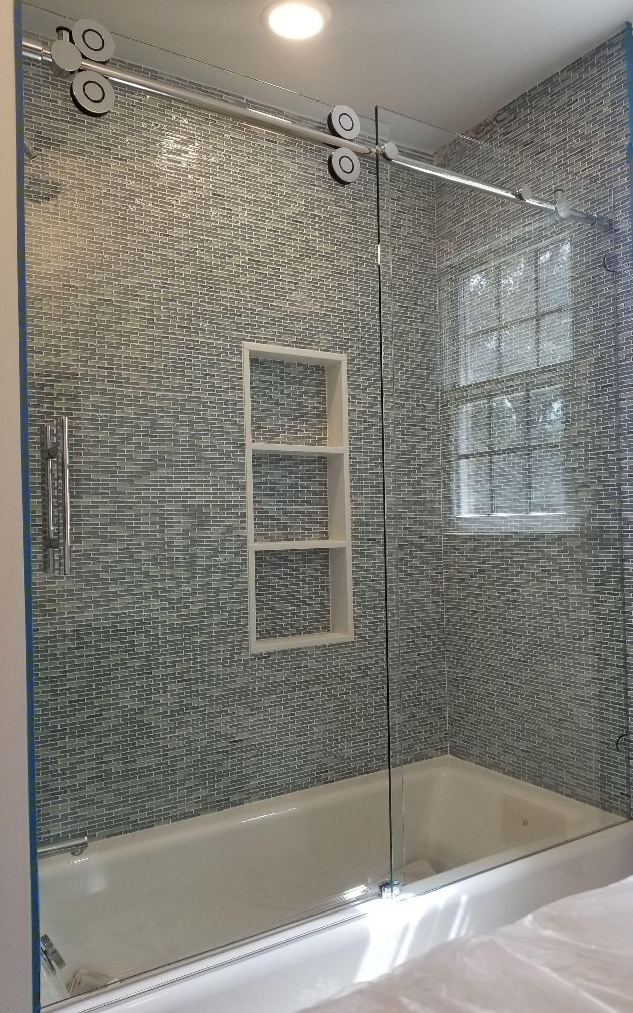 a bathroom with a sliding glass shower door and a bathtub.