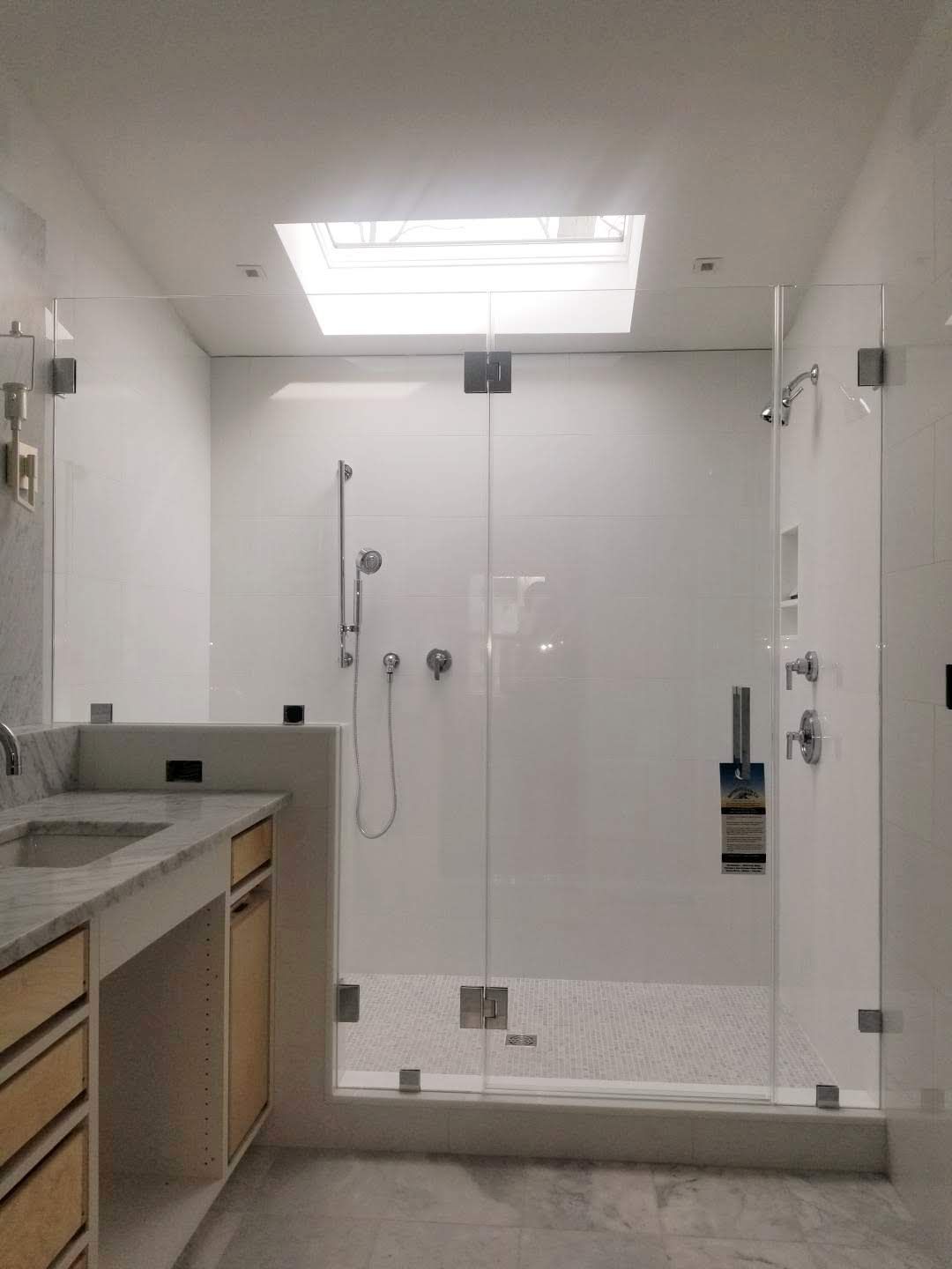 a bathroom with a sink , shower and skylight.