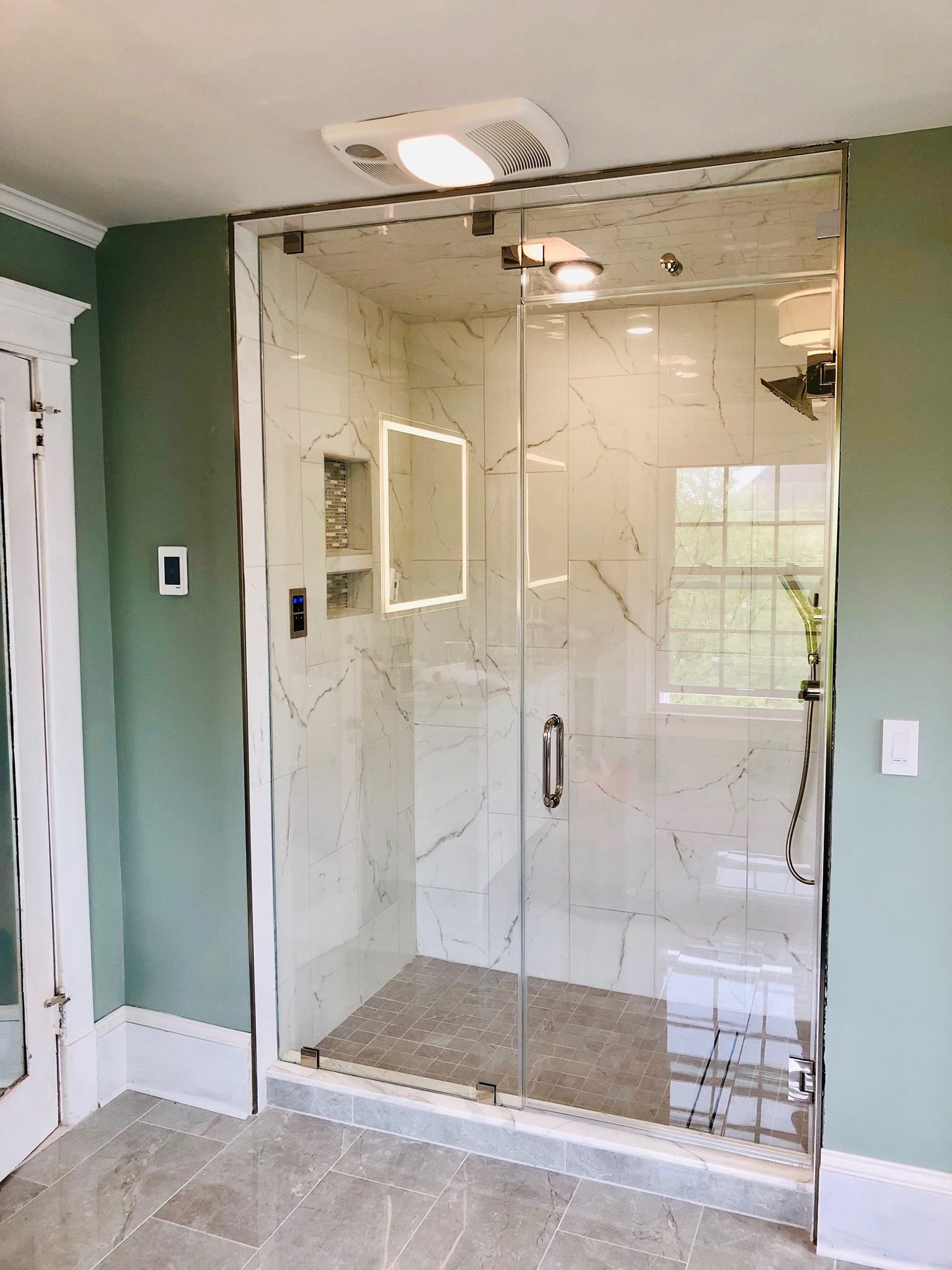a bathroom with a walk in shower with a glass door.