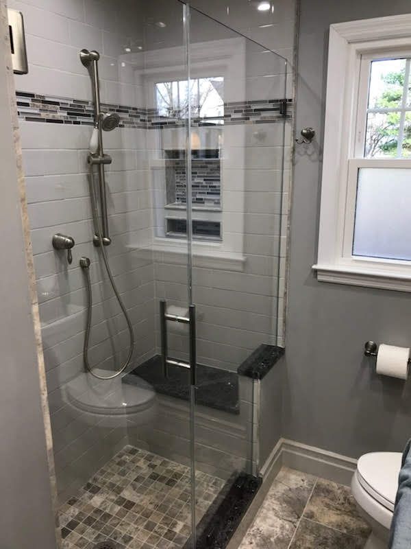 a bathroom with a walk in shower , toilet and window.