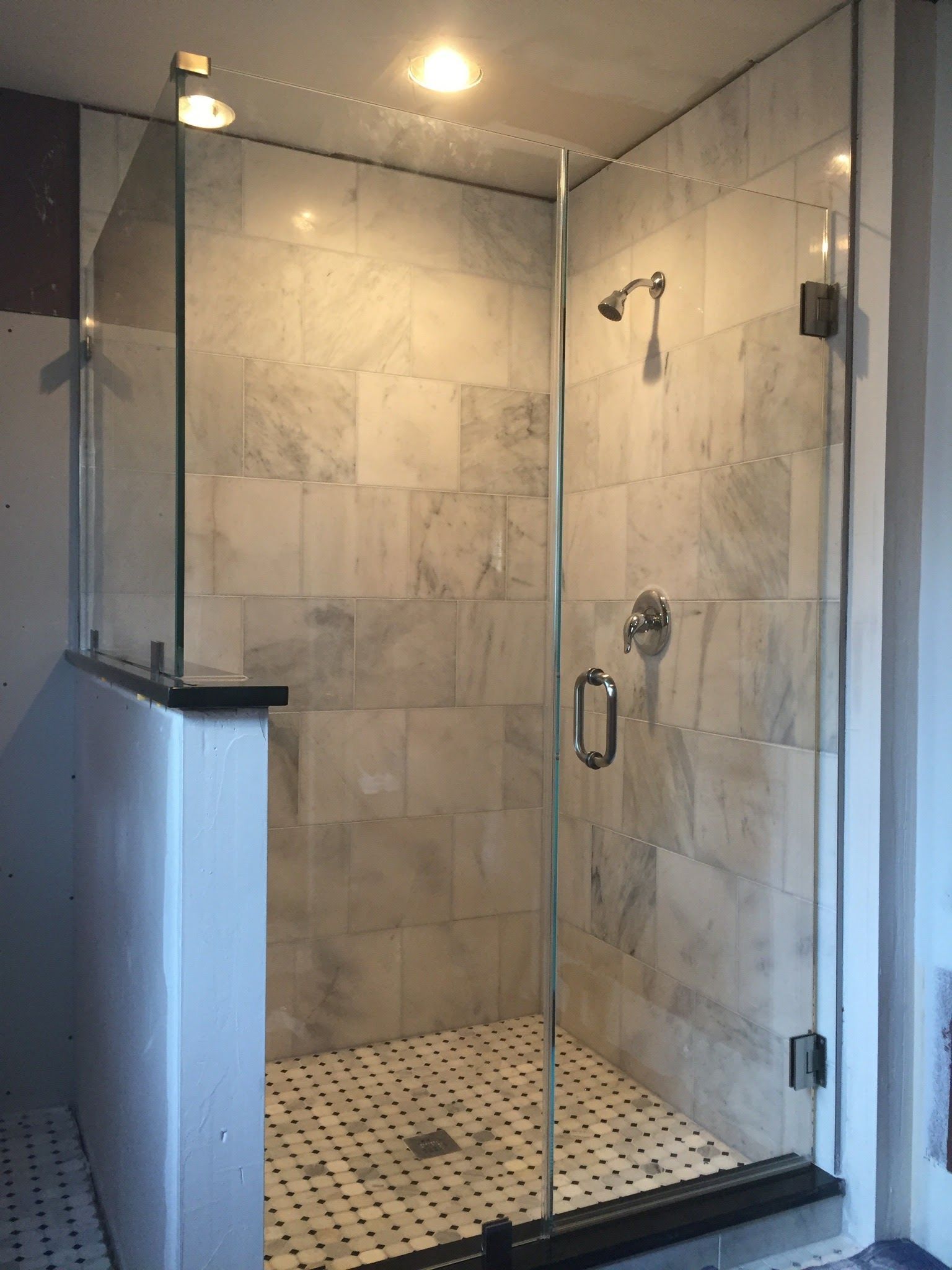 a bathroom with a walk in shower with a glass door.