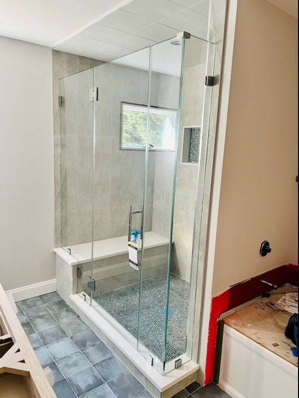 a bathroom with a glass shower door and a bench.