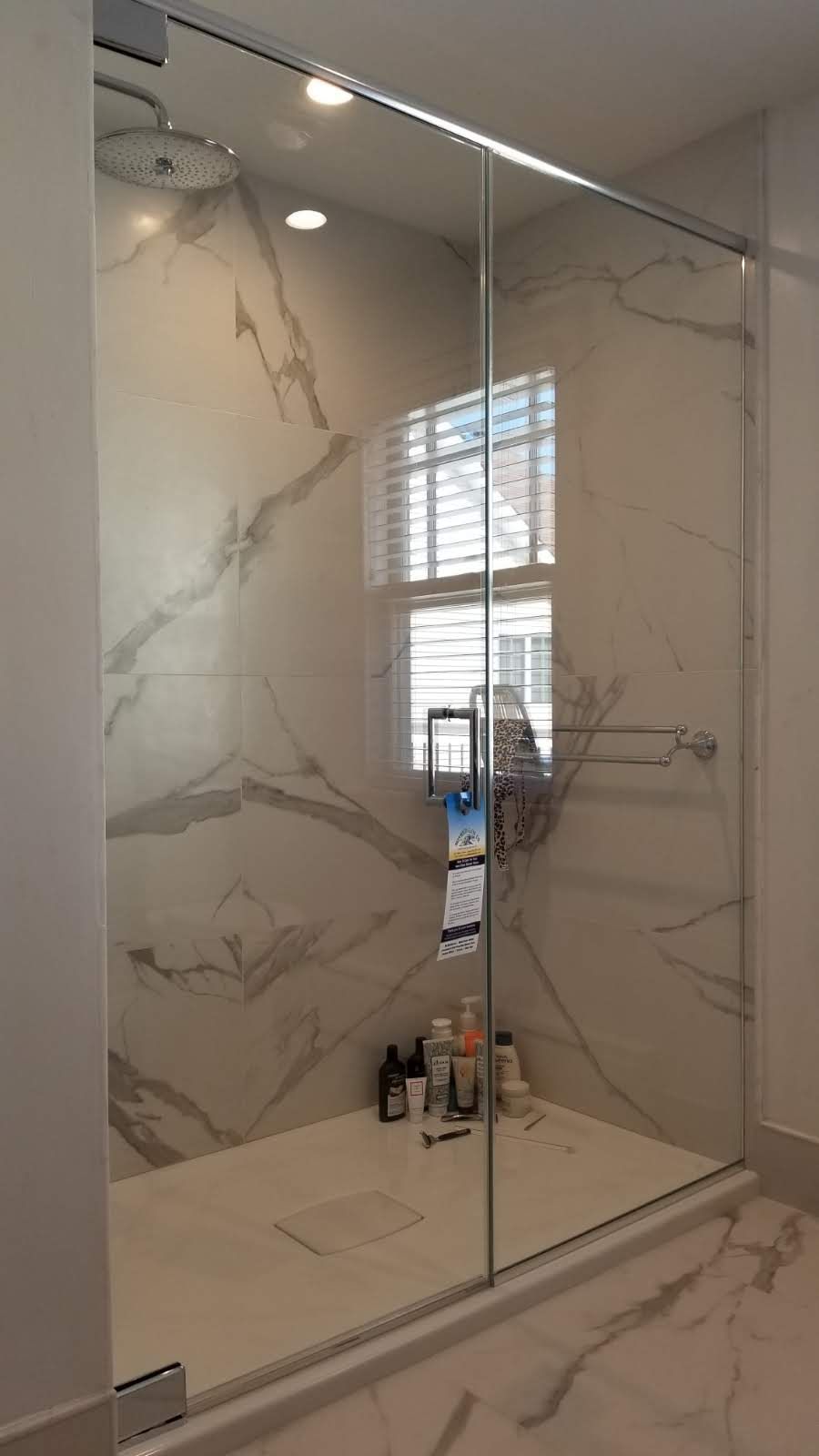 a bathroom with a sliding glass shower door and marble walls.
