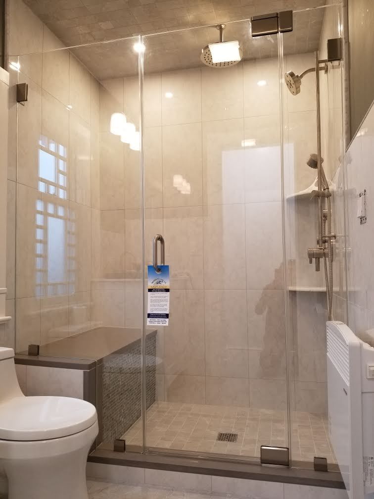a bathroom with a toilet and a walk in shower with a glass door.