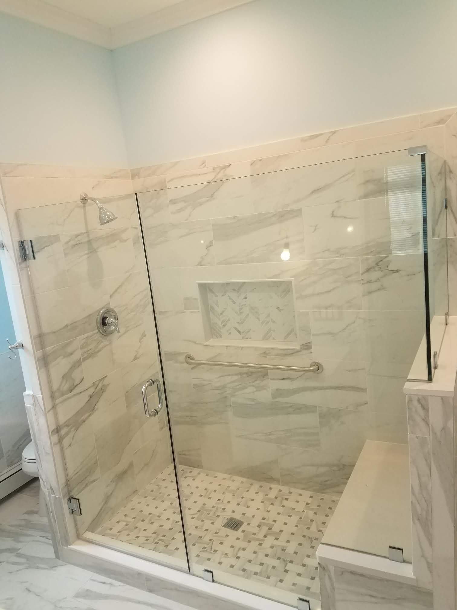 a bathroom with a walk in shower with a glass door.