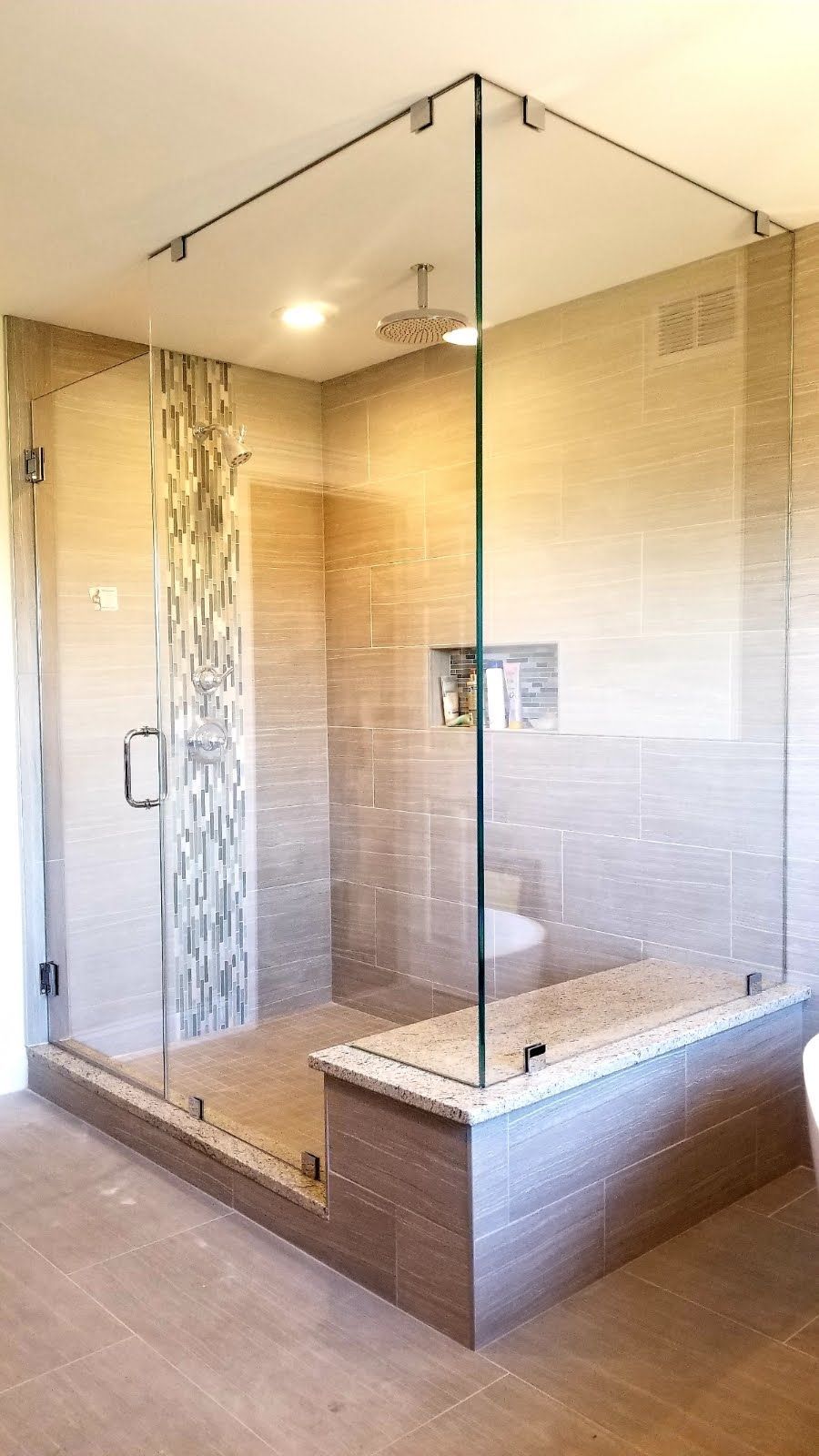 a bathroom with a walk in shower with a glass door.