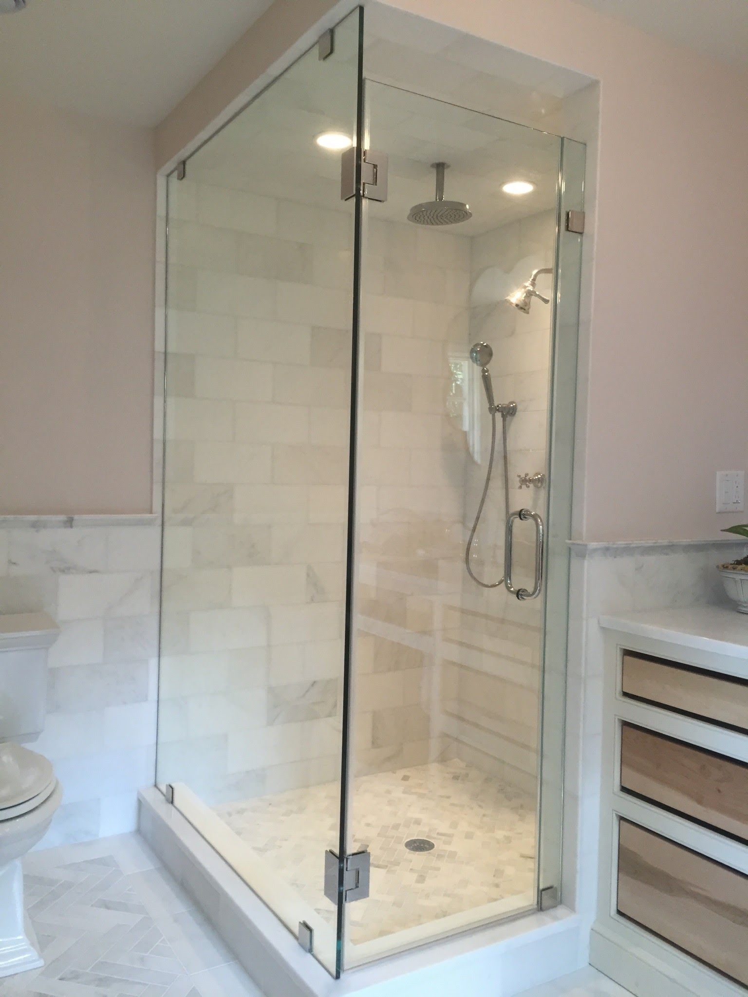 a bathroom with a walk in shower with a glass door.