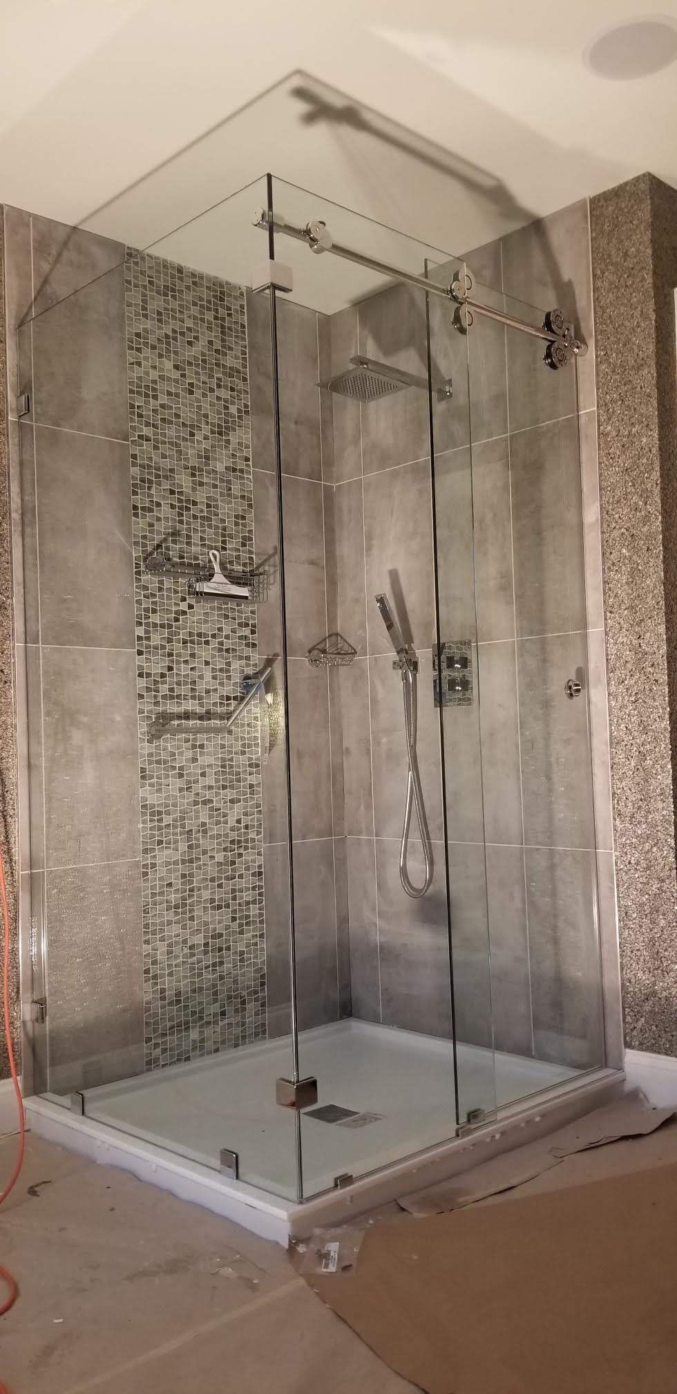 a bathroom with a walk in shower with a glass door.