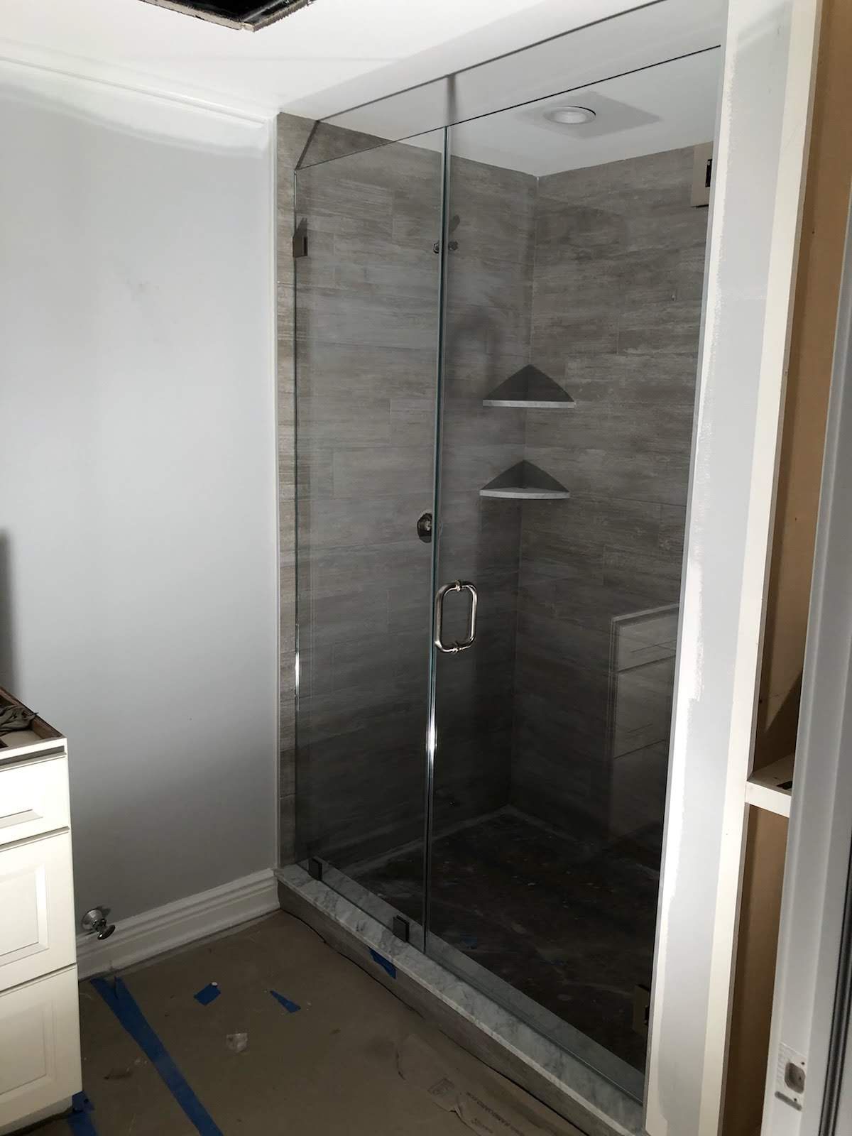 a bathroom with a glass shower door and shelves.