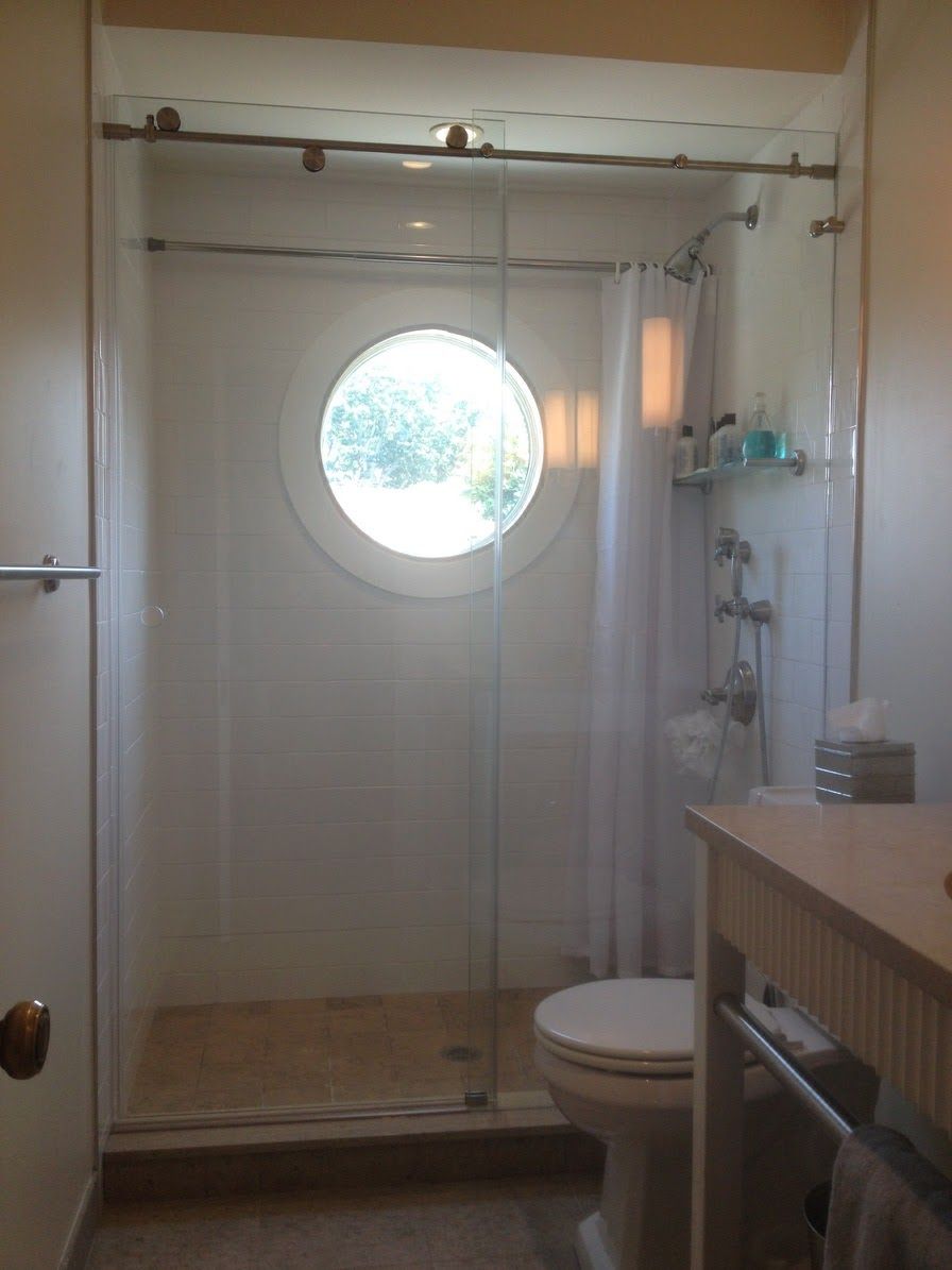 a bathroom with a toilet and a shower with a round window.