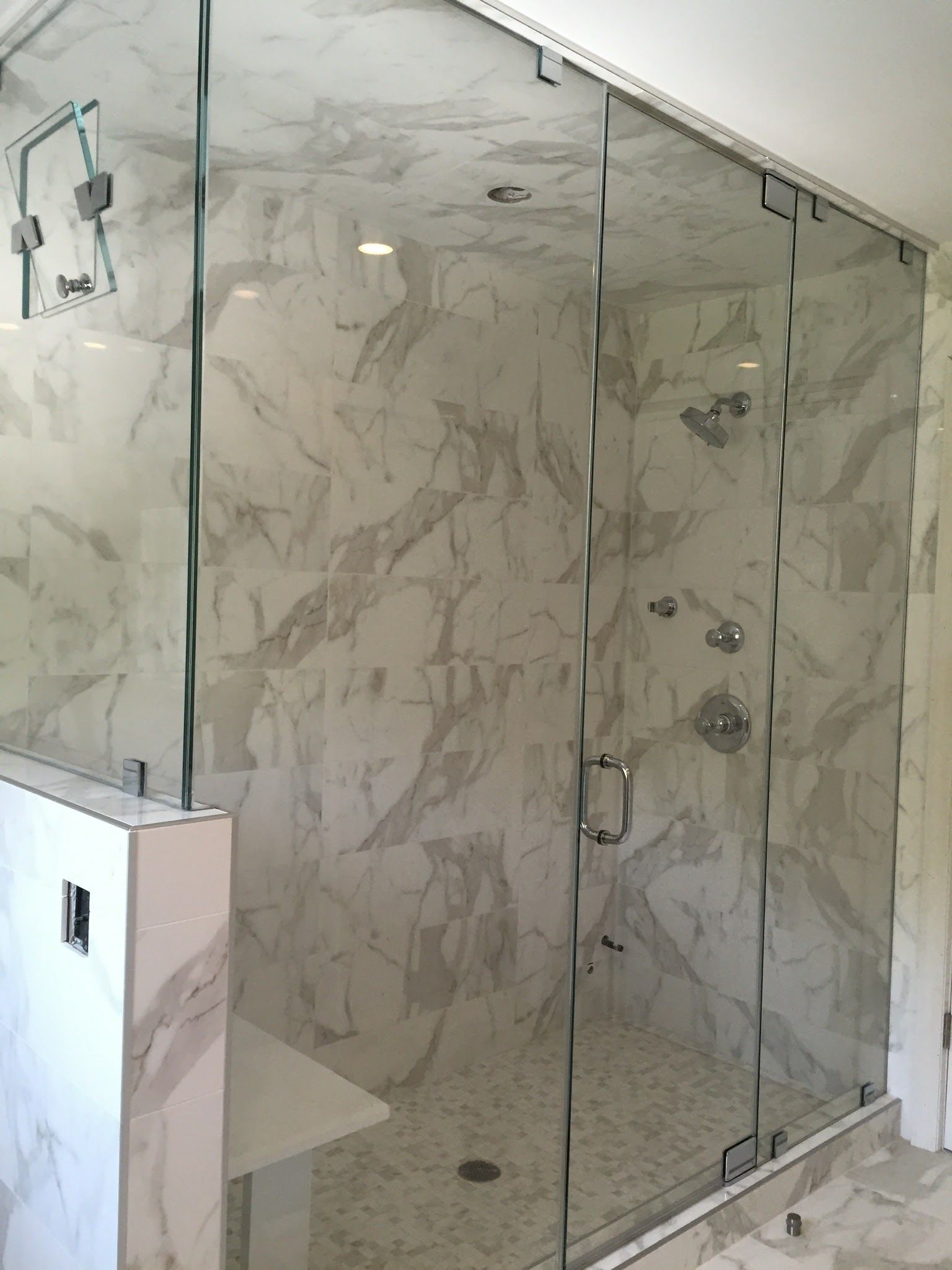 a bathroom with marble walls and a glass shower door.