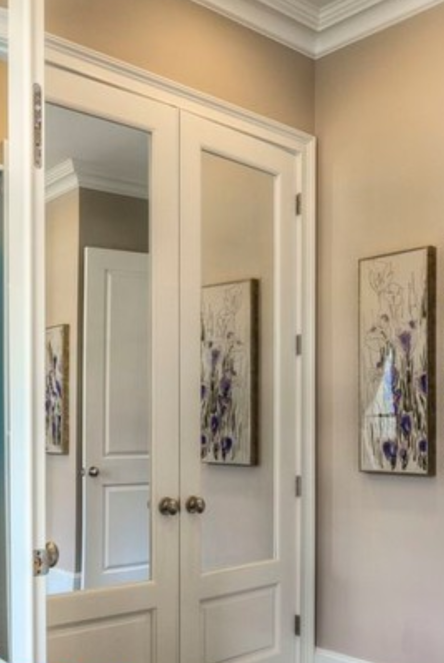 a closet with a mirror and paintings on the wall.
