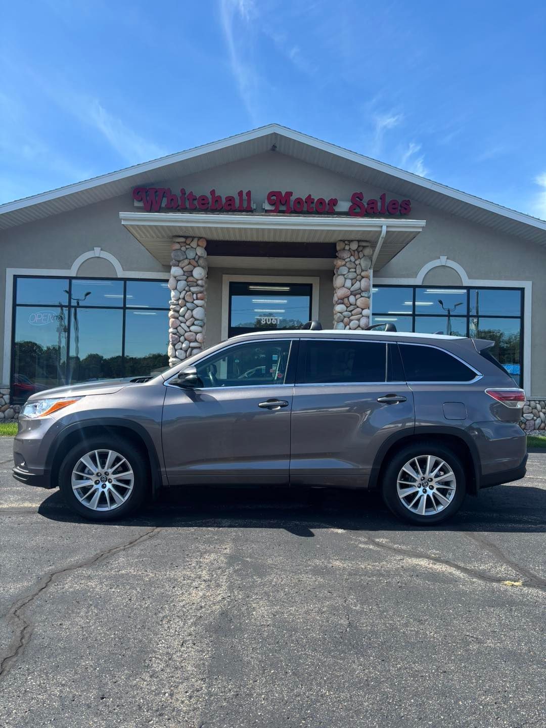 Gray Toyota SUV parked in front of Whitehall Motor Sales on a sunny day.