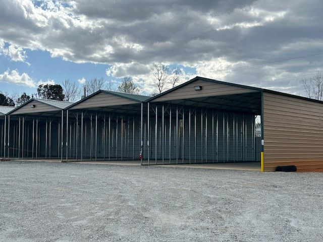 A row of metal buildings are lined up in a parking lot.