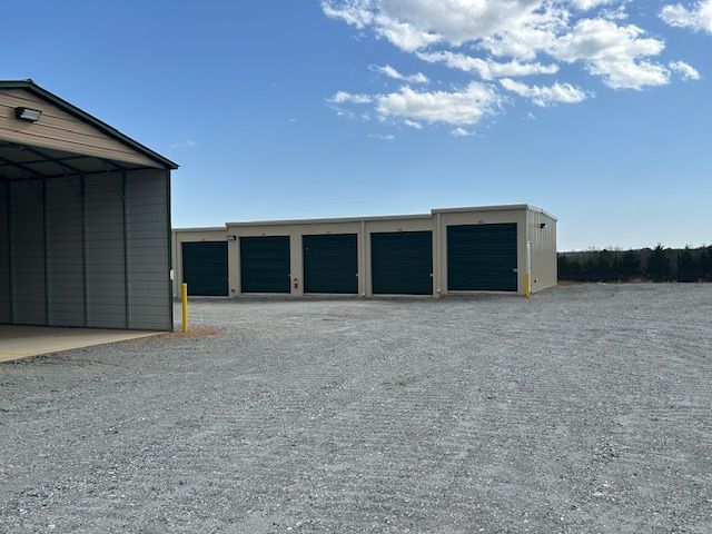 A building with two green garage doors and a white door.