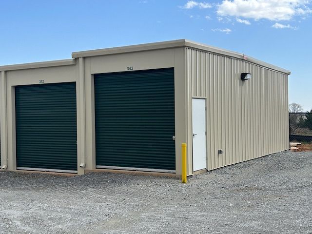 A building with two green garage doors and a white door.