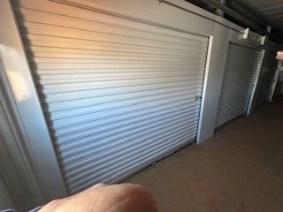 A person is pointing at a row of white garage doors.