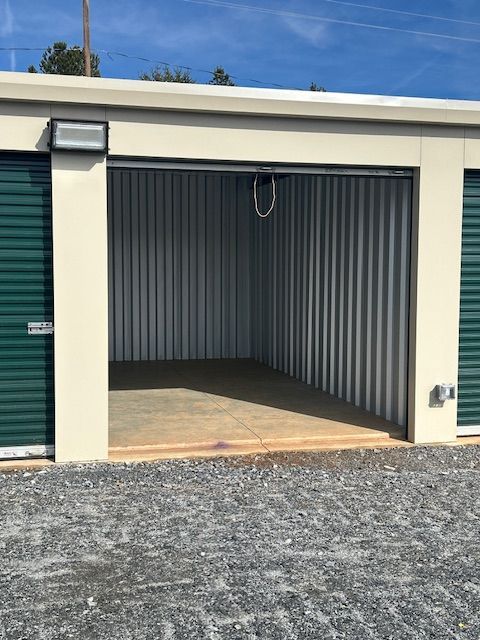 An empty storage unit with green doors and a light on the side.