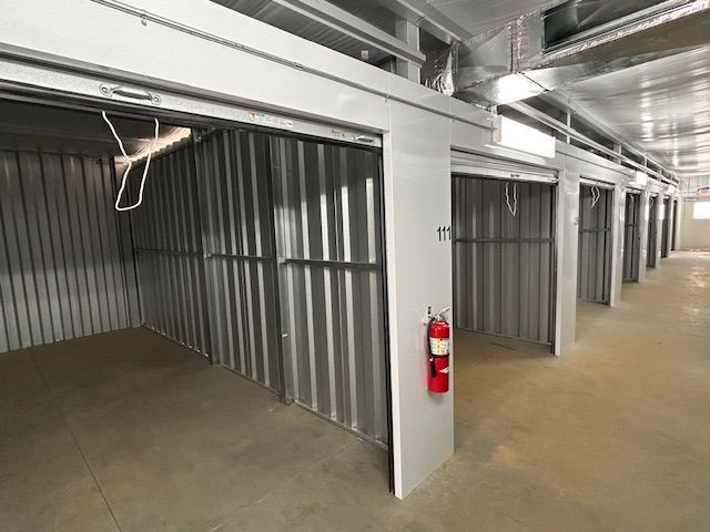 A row of empty storage units with a fire extinguisher on the wall.