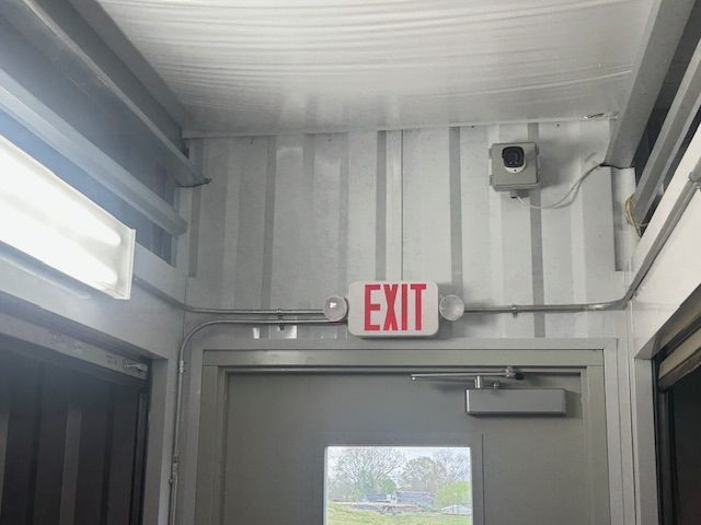 A red exit sign is above a door in a hallway.