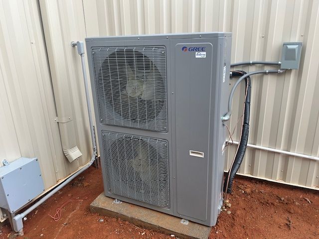 A large air conditioner is sitting outside of a building.