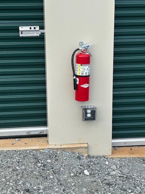 A red fire extinguisher is attached to a wall next to a green door