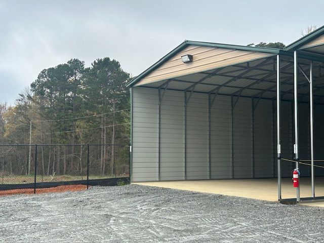 A large metal building is sitting on top of a gravel lot.